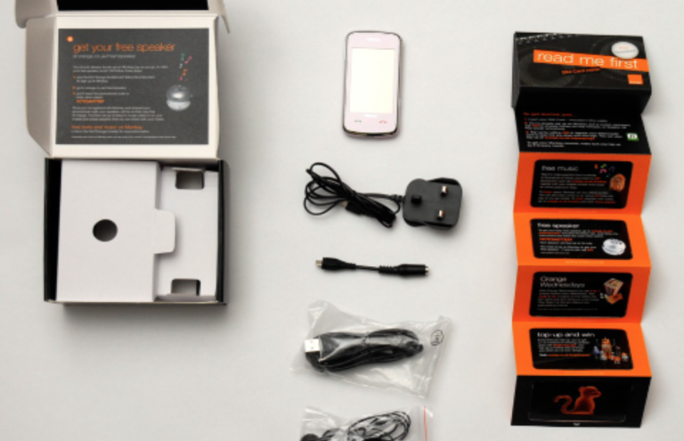 A smartphone with accessories and packaging laid out on a flat surface.